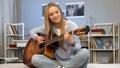 Young lady playing guitar in her room, writing song, dreaming of music career