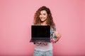 Young lady pointing at copy space on laptop isolated over pink Royalty Free Stock Photo