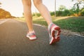 Young lady running on road closeup on shoe., at time sunset