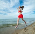 Young lady running at the sunny summer sand beach. Workout. Jog Royalty Free Stock Photo