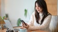 Young lady sits at the cafe, reading online business news on her smart phone Royalty Free Stock Photo