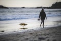 Young lady standing on the coast of the ocean crashed by foamy waves