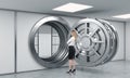 Young lady standing in front of a big unlocked round metal safe