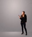 Young lady standing and holding a phone with copy space