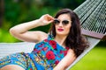 Young lady in sunglasses with long dark hair relaxing in hammock Royalty Free Stock Photo