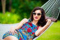 Young lady in sunglasses with long dark hair relaxing in hammock Royalty Free Stock Photo