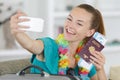 young lady taking selfie holding passport and tickets