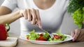 Young lady taking tomato salad fork from dinner plate, healthy snack, vitamins