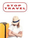 Young lady tourist with hat on face keeps hands crossed on chest near yellow suitcase on wheels isolated on white. Stop travel