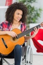 Young lady in wheelchair playing guitar Royalty Free Stock Photo