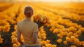 Young lady in a yellow t-shirt and jeans standing in the field of yellow tulips holding the bouquet of tulips. Royalty Free Stock Photo