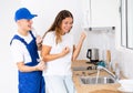 Young landlady of the apartment checks the repair work on fixing the faucet in the kitchen