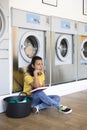 Young latin american woman bored while waiting for clothes washing at the self-service laundry Royalty Free Stock Photo