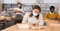 Young latin american woman in protective mask studying in library Royalty Free Stock Photo