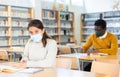 Young latin american woman in protective mask studying in library Royalty Free Stock Photo