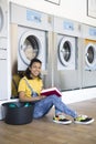 Young latin american woman waiting for her clothes to be washed in self-service laundromat