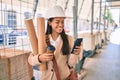 Young latin architect girl holding blueprints and using smartphone at the city Royalty Free Stock Photo