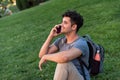 Young latin man sitting in the grass talking by mobile phone. Royalty Free Stock Photo