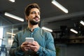 Young Latin business man entrepreneur holding mobile phone standing in office. Royalty Free Stock Photo