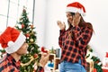 Young latin couple celebrating christmas holding engagement ring for wedding proposal at home