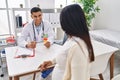 Young latin couple doctor and patient having medical session holding urine test tube at clinic Royalty Free Stock Photo