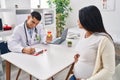 Young latin couple doctor and patient having medical session holding urine test tube at clinic Royalty Free Stock Photo