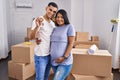 Young latin couple expecting baby hugging each other holding key at new home Royalty Free Stock Photo