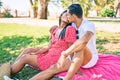 Young latin couple hugging and kissing sitting on the grass at the park Royalty Free Stock Photo