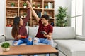 Young latin couple playing video game high five sitting on the sofa at home Royalty Free Stock Photo