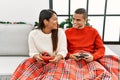 Young latin couple playing video game sitting on the sofa at home Royalty Free Stock Photo