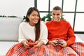 Young latin couple playing video game sitting on the sofa at home Royalty Free Stock Photo