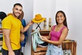 Young latin couple smiling happy choosing handbag at clothing store