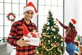 Young latin couple smiling happy decorating christmas tree at home