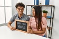 Young latin couple smiling happy holding our first home blackboard at house Royalty Free Stock Photo