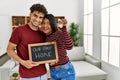 Young latin couple smiling happy holding our first home blackboard and key at house Royalty Free Stock Photo