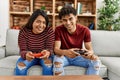 Young latin couple smiling happy playing video game sitting on the sofa at home Royalty Free Stock Photo