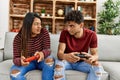 Young latin couple unhappy playing video game sitting on the sofa at home Royalty Free Stock Photo