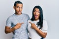 Young latin couple wearing casual clothes surprised pointing with finger to the side, open mouth amazed expression Royalty Free Stock Photo