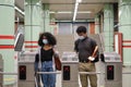 Young latin couple wearing protective face mask walking through subway turnstile at the train or metro station