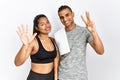 Young latin couple wearing sportswear standing over isolated background showing and pointing up with fingers number eight while Royalty Free Stock Photo