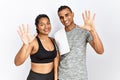 Young latin couple wearing sportswear standing over isolated background showing and pointing up with fingers number ten while Royalty Free Stock Photo