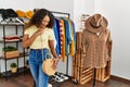 Young latin customer woman smiling happy choosing handbag at clothing store