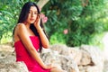 Young Latin girl with long black hair and red dress looking to the side