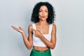 Young latin girl pointing open palm with finger looking at the camera blowing a kiss being lovely and sexy Royalty Free Stock Photo