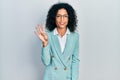 Young latin girl wearing business clothes and glasses showing and pointing up with fingers number four while smiling confident and Royalty Free Stock Photo