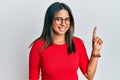 Young latin girl wearing casual clothes and glasses smiling with an idea or question pointing finger up with happy face, number Royalty Free Stock Photo