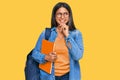 Young latin girl wearing student backpack and holding books with hand on chin thinking about question, pensive expression Royalty Free Stock Photo