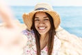 Young latin girl wearing summer hat making selfie by the camera at the beach Royalty Free Stock Photo