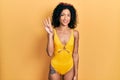 Young latin girl wearing swimsuit showing and pointing up with fingers number four while smiling confident and happy Royalty Free Stock Photo