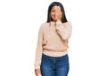 Young latin girl wearing wool winter sweater covering one eye with hand, confident smile on face and surprise emotion Royalty Free Stock Photo